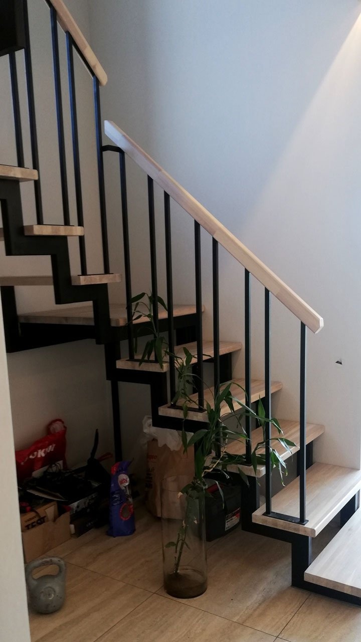 Лестница на двух косоурах с ограждением черного цвета в современном стиле с деревянным поручнем, вид снизу сбоку