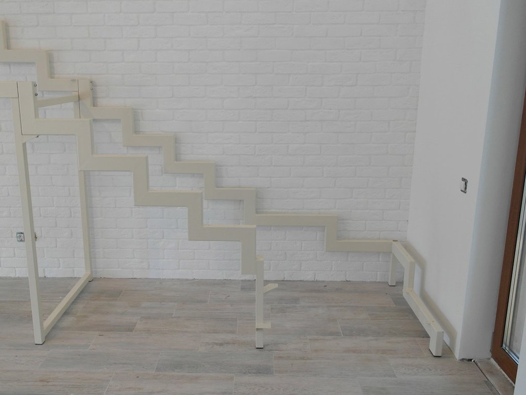 Белый каркас г-образной лестницы с поворотом, вид снизу